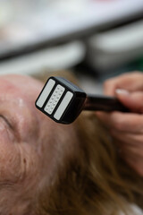 Elderly woman receiving radiofrequency lifting procedure for face skin rejuvenation and anti-age at aesthetic cosmetology center. RF lifting in beauty clinic.