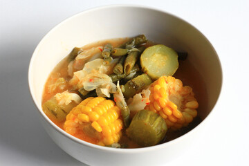 Sayur asem or sayur asam is a popular Indonesian vegetable in tamarind soup, isolated on white background. Common ingredients are chayote, long beans and corn with the addition of tamarind or bilimbi.
