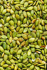 Raw pumpkin seeds, dried and peeled, food background texture, top view