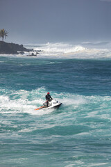 Obraz premium Rescue lifeguard riding a jet sky during big winter swell at North shore Oahu Hawaii, looking and helping surfers 