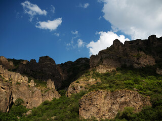 Fototapeta na wymiar Beautiful landscape, steep slope, rocky ridge in the gorge, blue sky with fluffy clouds, wallpaper