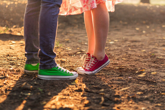A woman stands on her tiptoes to kiss a man. A man and a woman in the same sneakers of different colors. Valentine's Day