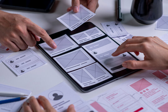 Close up ux developer and ui designer brainstorming about mobile app interface wireframe design on table.