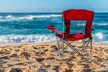 An empty red beach chair facing the water on Sunset Beach, Hawaii