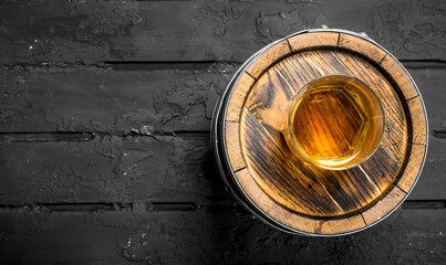 Whiskey in a glass on a barrel.