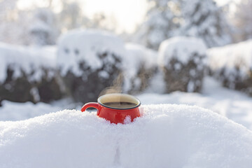 Red cup with coffee on snow in the park christmas background