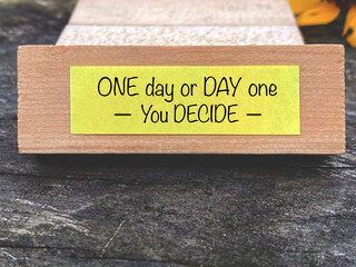 Inspirational and motivational quote. One day or day one text on yellow notepaper background.