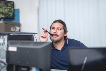 An office employee brainstorming for ideas. Biting his ballpen while thinking and analyzing.