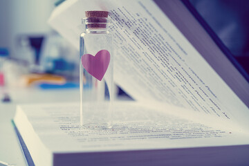 a small glass vial with a heart figurine inside on the spread of the book