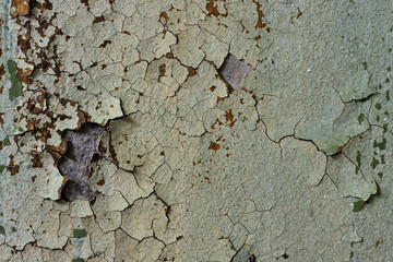Green peeling paint on the wall. Old concrete wall with cracked flaking paint. Weathered rough...