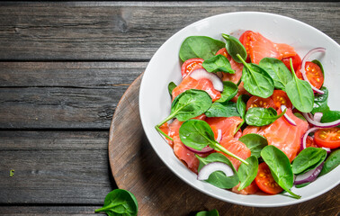 Fish salad. Salad with slices of salmon, tomatoes and spinach with lime juice.