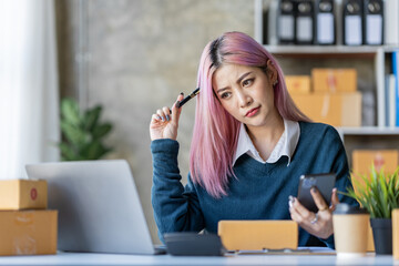 Portrait of an Asian businesswoman writing customer shipping information on a parcel box. She owns an online store. online selling concept.