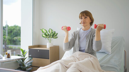 Old elderly caucasian patient or pensioner woman, doing exercise, working out on bed in nursing home in hospital. Senior people lifestyle activity recreation. Health care physical therapy.