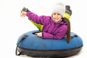 Little girl sliding downhill on tube