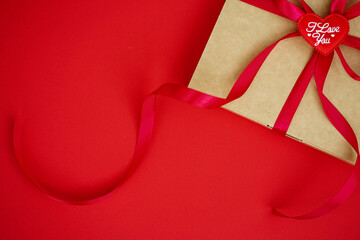 Paper art Valentine's day concept banner with handmade gift box, paper cutting ribbon, bow and many hearts on red background with space for text
