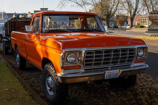 Headlights of orange Ford F250 custom Pickup. 1979 retro Ford parked at the street side on sunny autumn day. Snohomish, WA, USA - October 2022