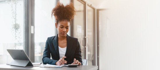 Young African American female working with tablet computer on remote project watching webinar. doing corporate data digital technology analysis.