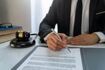 Young Asian legal advisor or lawyer looking at documents and checking accuracy in details of the Business agreement. Before signing. Sign the contract at the desk in the office.