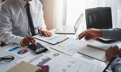Two young Asian businessmen have a meeting on a real estate project. Planning and calculating, clarifying the information in the graph analyzing business finance charts, and accounting concepts.