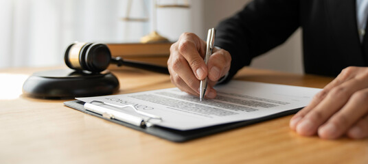 Asian female legal advisor or a lawyer using a pen to check business information and various details Business venture capital acknowledgment signing on paperwork at a desk in her office.