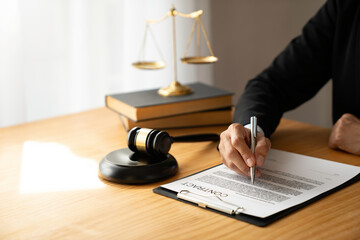 Asian female legal advisor or a lawyer using a pen to check business information and various details Business venture capital acknowledgment signing on paperwork at a desk in her office.