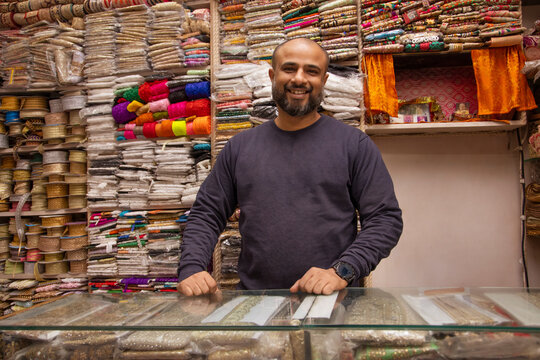 Portrait of a cheerful male shop keeper standing at his lace shop