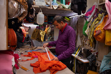 Portrait of a tailor measuring cloth in his workshop