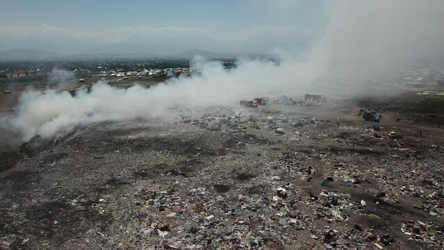 Drone flying over a smoking city dump. Smoke and stink.