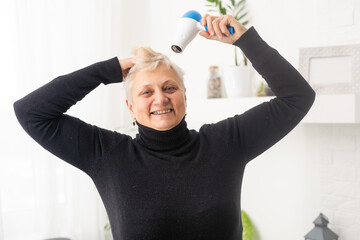senior woman drying her hair with a hair dryer