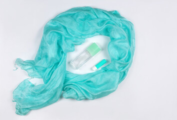  Aqua blue color natural silk ladies scarf, a lipstick and a  transparent bottle of perfume on white background. top view