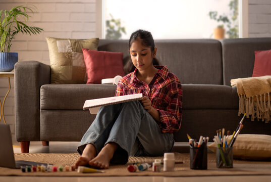 Portrait of a girl drawing in living room at home