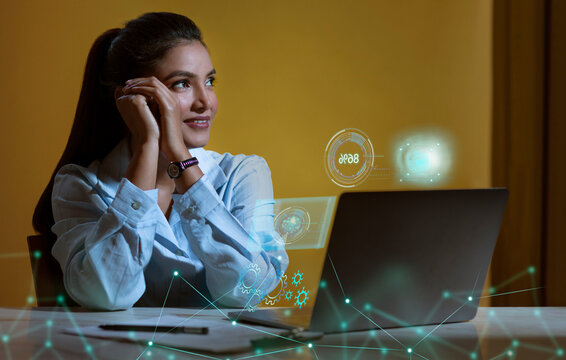 Businesswoman working on laptop computer with icons on virtual screen