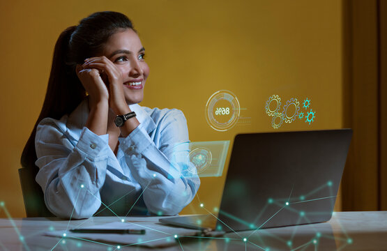 Businesswoman working on laptop computer with icons on virtual screen