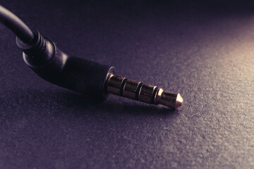 Macro of gold plated angle form audio cable 3.5mm jack over dark background - 561203699