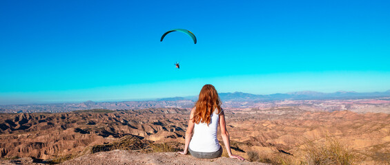 Traveler woman at Gorafe desert and paragliding- badlands near Guadix,  Spain - obrazy, fototapety, plakaty