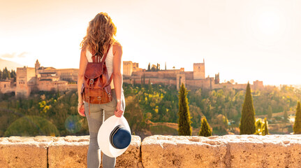 Woman tourist looking at Ancient arabic fortress Alhambra- Granada in Spain - obrazy, fototapety, plakaty