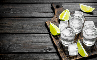 Vodka with ice on a cutting Board with slices of lime.