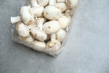 Champignon mushrooms in the plastic box at the grey background	