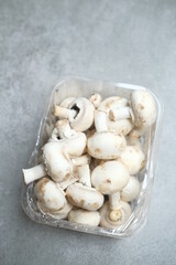Champignon mushrooms in the plastic box at the grey background	