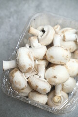 Champignon mushrooms in the plastic box at the grey background	