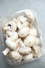 Champignon mushrooms in the plastic box at the grey background	