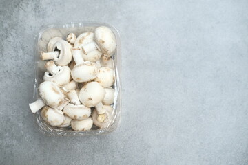 Fototapeta na wymiar Champignon mushrooms in the plastic box at the grey background 
