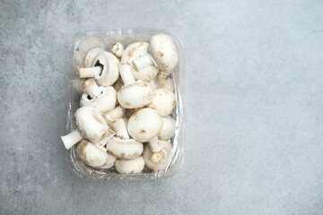 Fototapeta na wymiar Champignon mushrooms in the plastic box at the grey background 