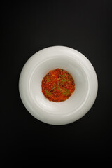 White plate with salted red caviar isolated over black background