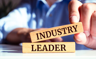 Closeup on businessman holding a wooden block with "Industry leader", Business concept