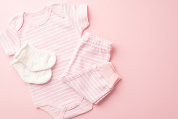Infant clothes concept. Top view photo of pink bodysuit pants and socks on isolated pastel pink background with empty space