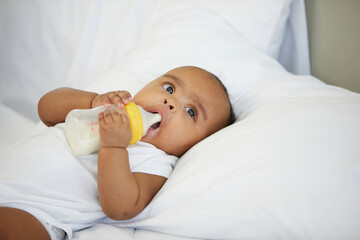 baby drinking a milk bottle on the bedroom