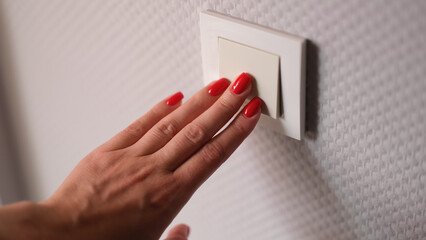 Closeup of woman hand is turned off on light switch at home