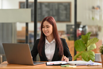 Fototapeta na wymiar Business and financial concept with Young Asian administrator clearing accounting paperwork on her office desk.