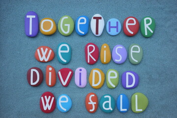 Together we rise, divided we fall, creative quote composed with multi colored stone letters over...